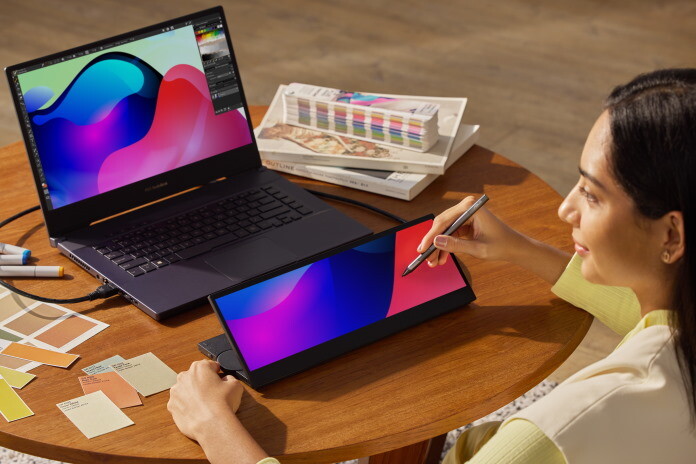 Designer working with dual monitors displaying vibrant gradient artwork and color swatches.