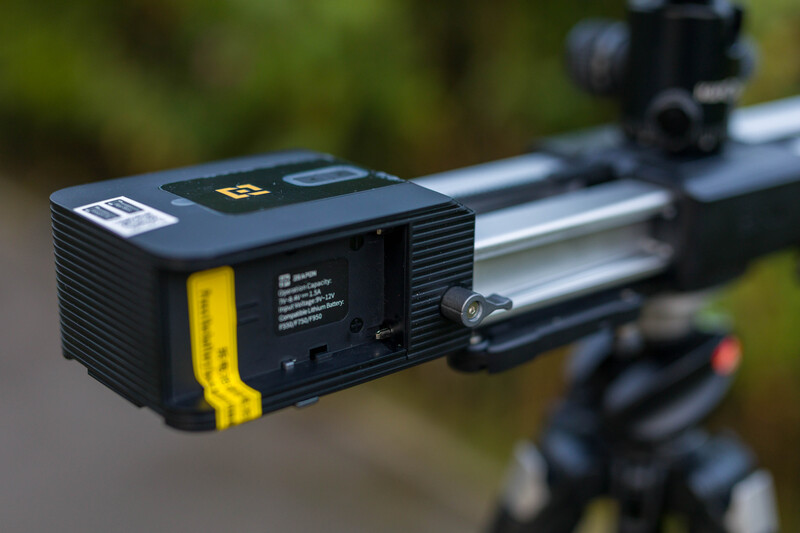 Black and yellow laser rangefinder mounted on rifle with scope in outdoor setting.