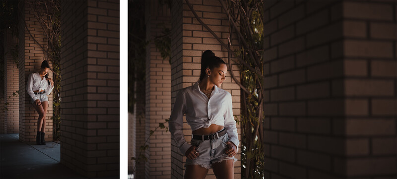 Woman in white button-up shirt and denim shorts posed against brick wall with ivy vines.