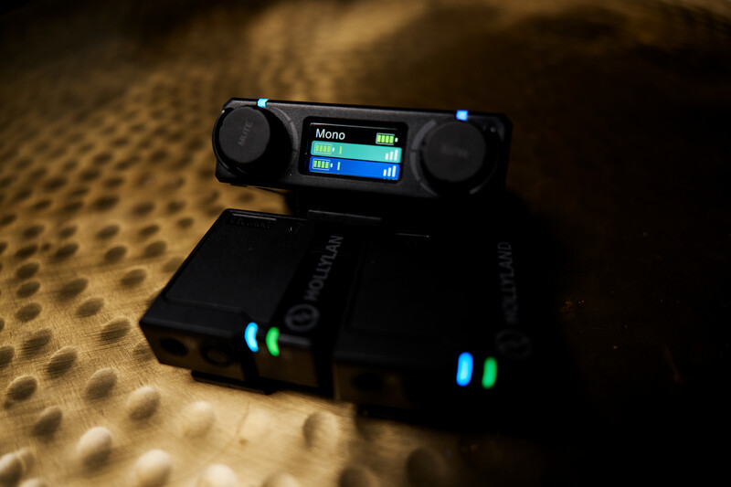 Wireless audio receiver and transmitter units with glowing blue LED indicators on a textured surface.