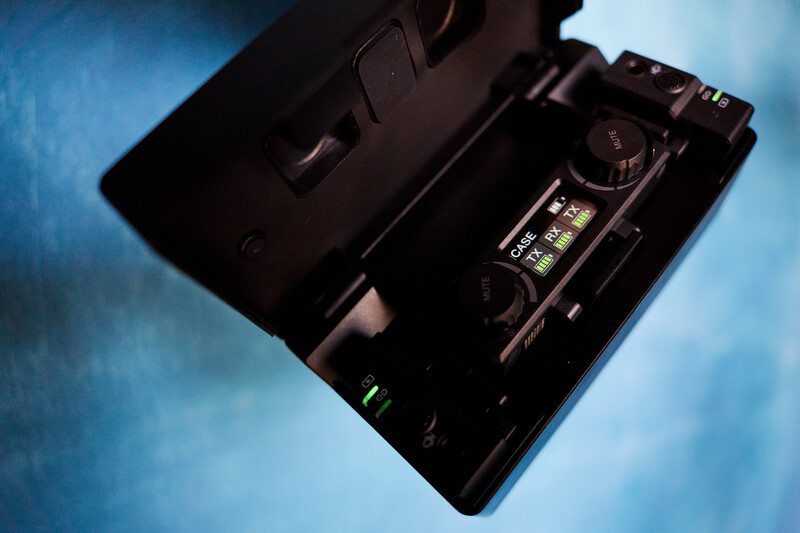Top-down view of an open black camera body showing internal mechanisms and controls against a blue textured background.