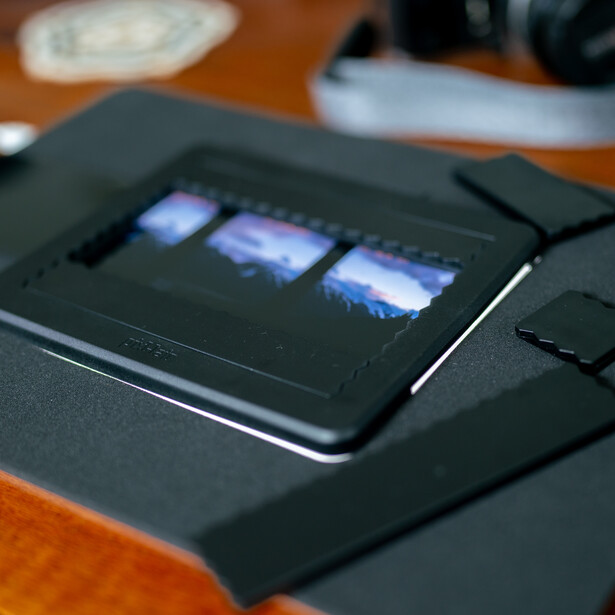 Black smartphone displaying three illuminated app icons on a dark surface against a wooden background.