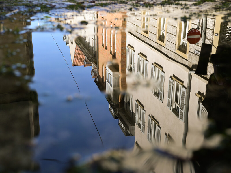 Inverted reflection of historic buildings mirrored in still floodwater on a city street.