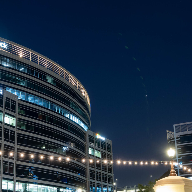 Curved modern building facade illuminated at night with blue-toned sky and stars visible.