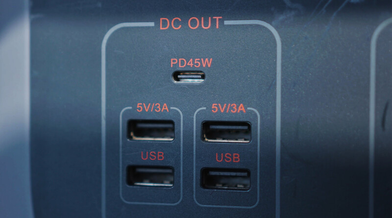 Close-up of a power delivery charging hub with multiple ports labeled for USB and DC output.