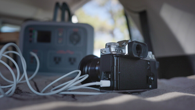 Vintage film camera with lens attached next to a power supply unit and coiled white cables on a table.