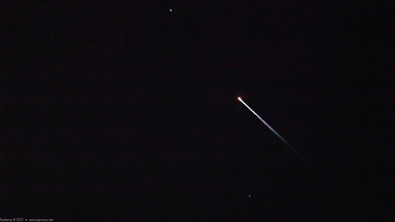 Bright streak of light crossing a dark night sky, possibly a meteor or satellite.