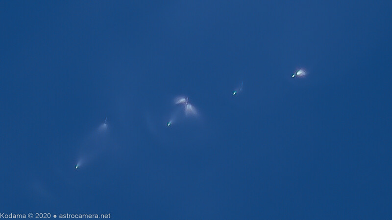 String of bright lights streak across a deep blue twilight sky in diagonal formation.