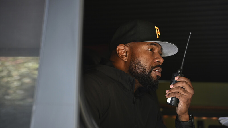 Man wearing a baseball cap holding a radio transmitter at night outdoors.