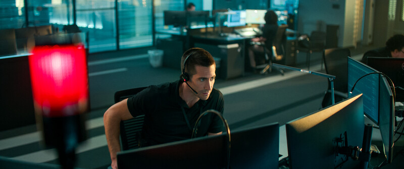 Man wearing headset working at computer desk in modern office with red accent lighting.