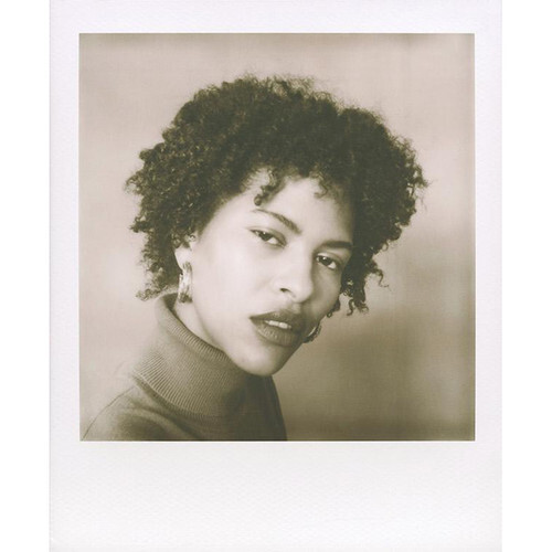 Portrait of a person with short curly hair, looking over their shoulder with a subtle expression.
