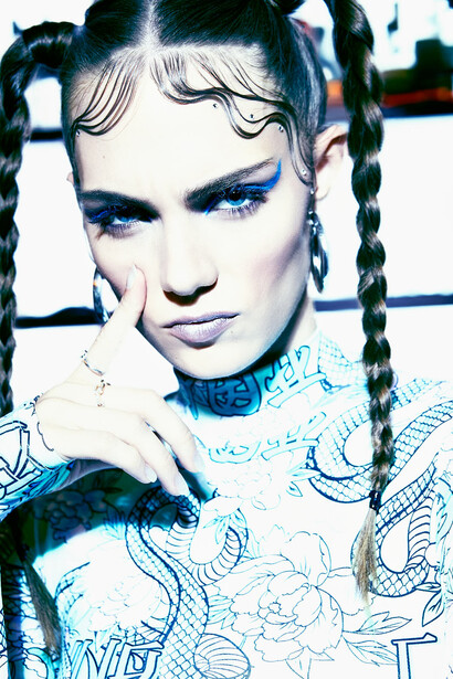 Portrait of person with graphic blue eyeshadow, braided hair, and digital overlay effects.