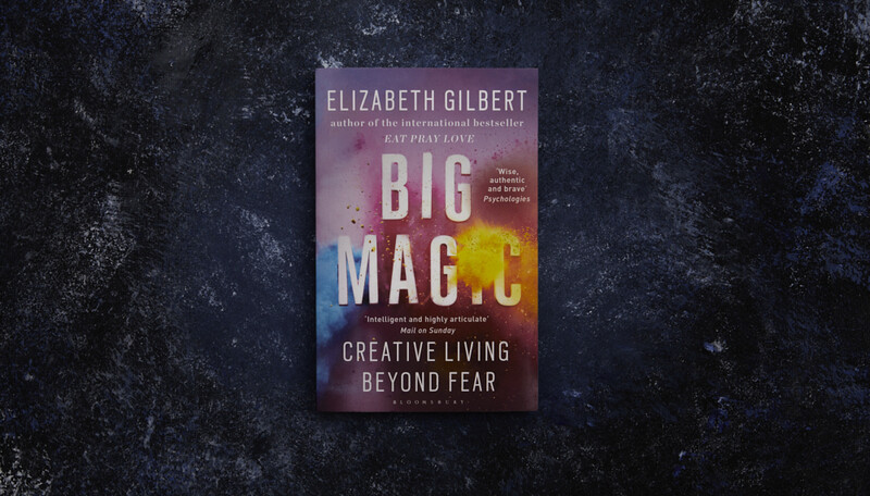 Book cover for "Big Magic: Creative Living Beyond Fear" by Elizabeth Gilbert displayed on a dark textured surface.