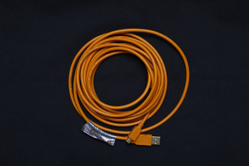 Orange coiled USB cable with connector ends against black background.