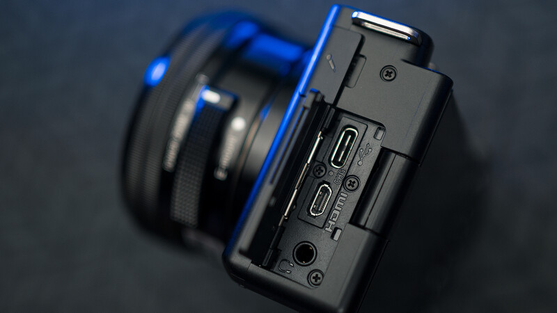 Close-up of a compact camera's right side panel showing control buttons and ports against a dark background.