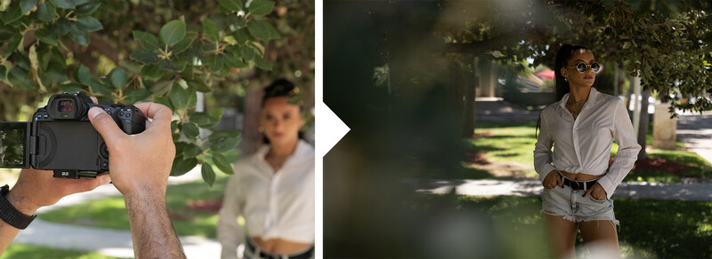 Photographer holding a DSLR camera while composing a portrait of a woman outdoors under tree shade.