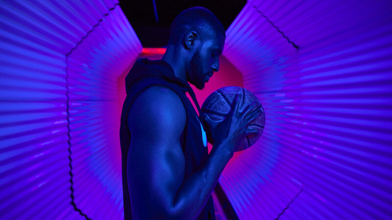 Male figure in boxing stance within neon-lit corridor with purple and blue lighting.