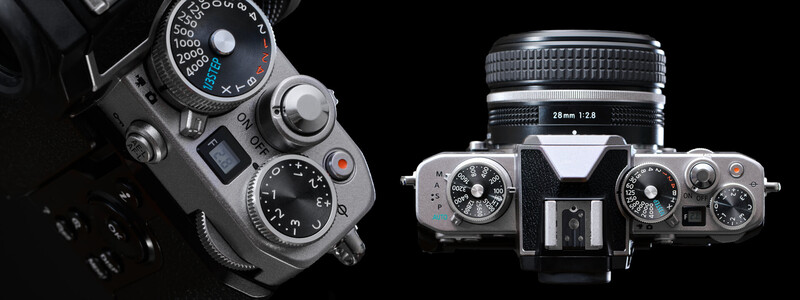 Top-down view of two vintage rangefinder cameras with manual controls and interchangeable lenses on black background.