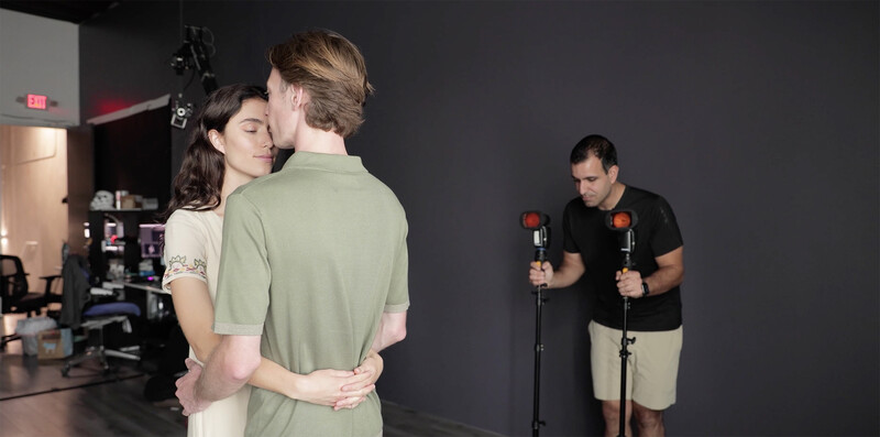 Two people embracing during a studio portrait session with professional lighting equipment visible in the background.