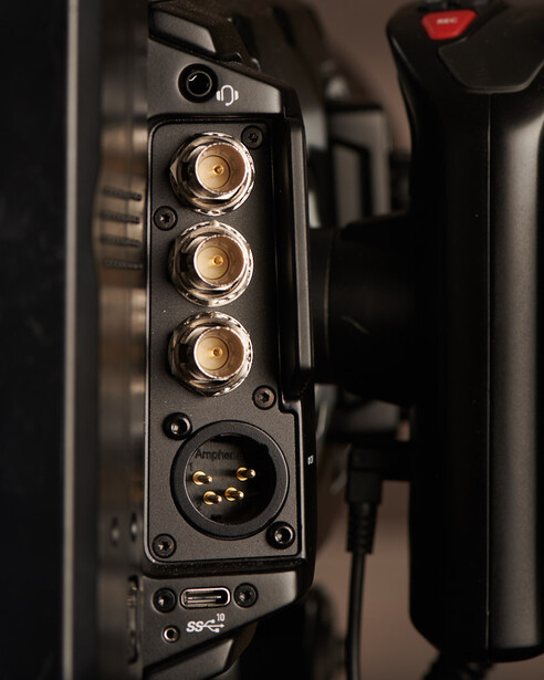 Close-up of professional camera connector panel with three round ports and XLR socket against dark housing.