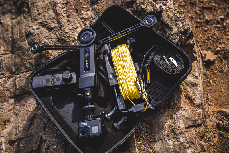 Overhead view of professional video camera equipment and accessories arranged on textured ground.
