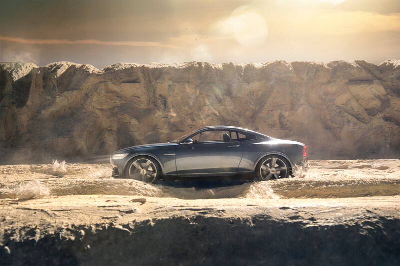Silver sedan parked on desert terrain with snow-capped mountains under golden hour sky.