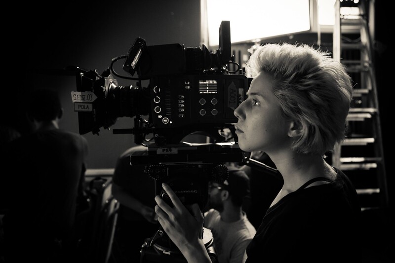 Cinematographer operating a professional cinema camera in black and white lighting.