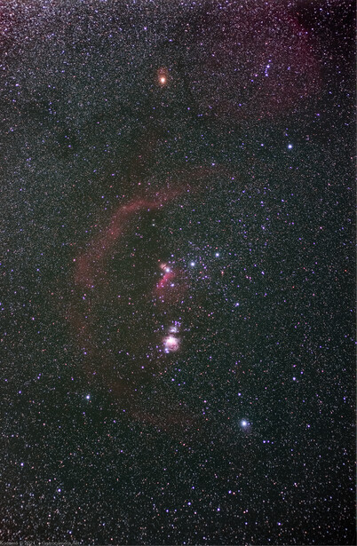 Deep-space astrophotography showing star field with nebulosity and emission regions in red and purple hues.