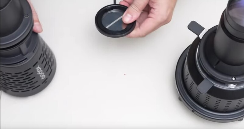 Hands holding camera lens caps and filters during equipment setup or comparison.