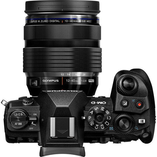 Olympus OM-D mirrorless camera with 12-45mm lens mounted, shown from top-down view with controls visible.