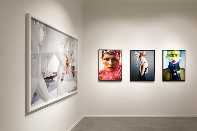Gallery wall with one large framed photograph on the left and three smaller framed portraits arranged on the right wall.