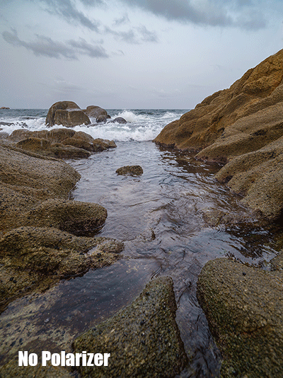 Rocky tidal pool surrounded by boulders and rough coastline under overcast sky.