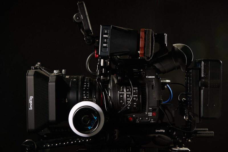 Canon cinema camera with follow focus system and monitor mounted on black support rig.