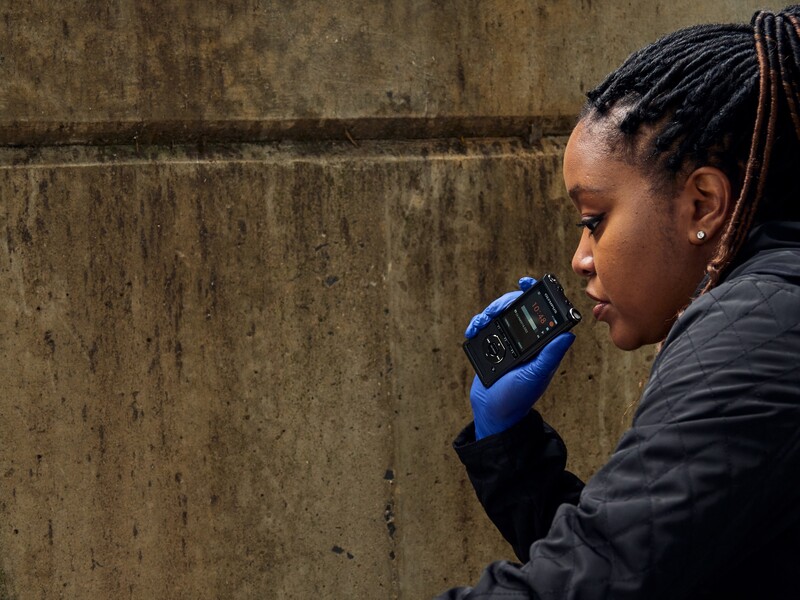 Woman in profile speaking on a mobile phone against a weathered concrete wall.