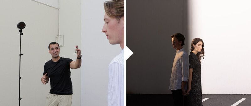 Behind-the-scenes photography setup showing a man directing talent near a studio light, with two women positioned as subjects in a minimalist white and gray environment.