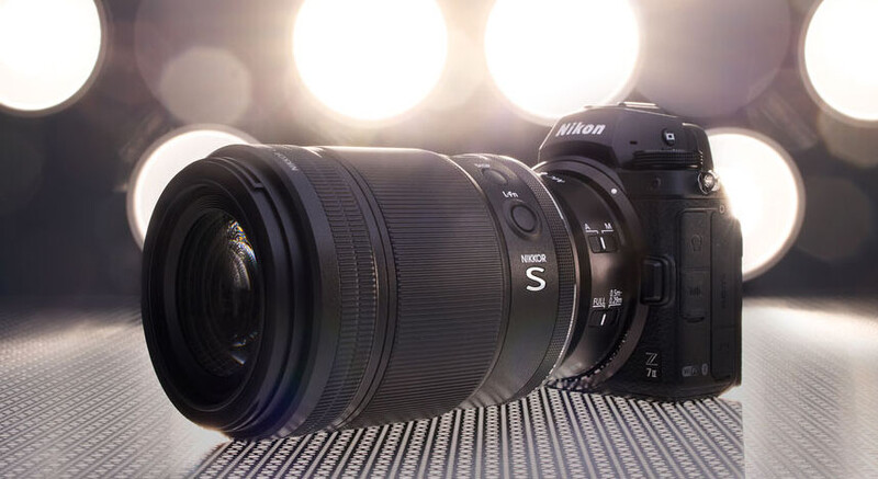 Nikon Z mirrorless camera with attached zoom lens on textured surface under warm studio lights.