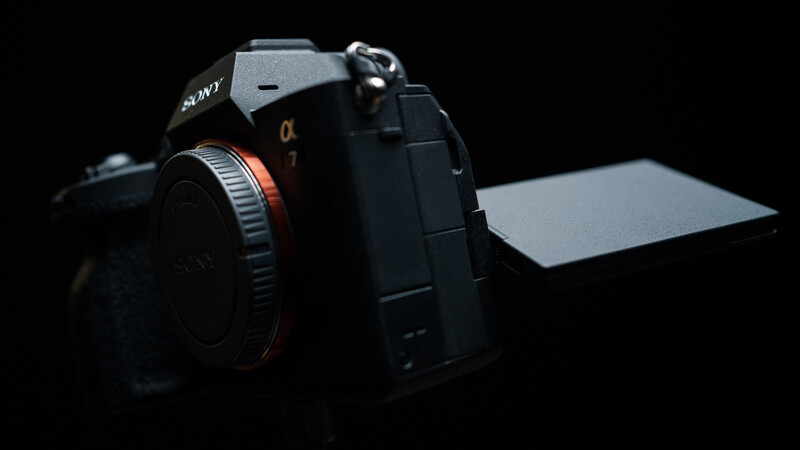 Sony mirrorless camera with articulating screen against dark background with studio lighting.
