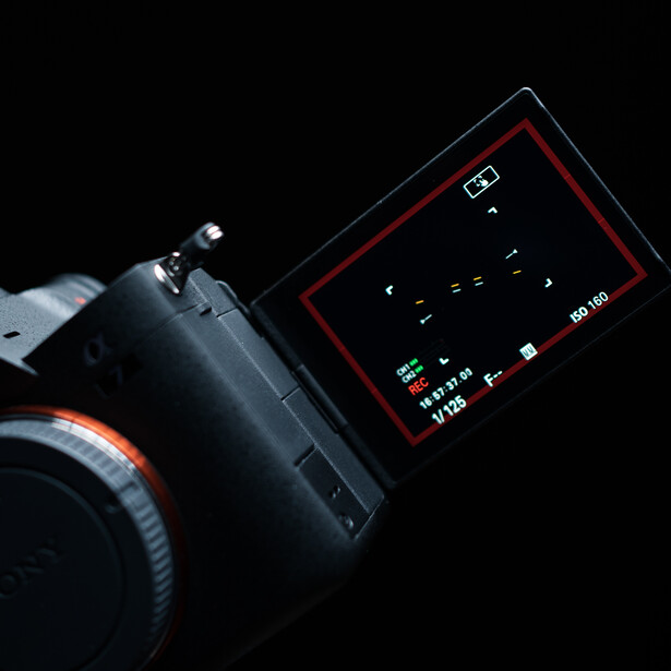 Professional video camera with flip-out LCD screen displaying menu options against black background.