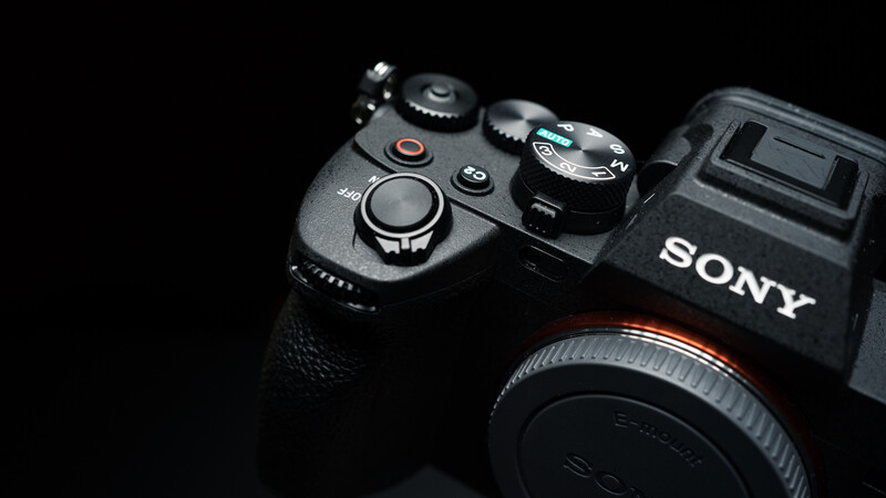 Sony mirrorless camera body with control dial and grip visible against black background.