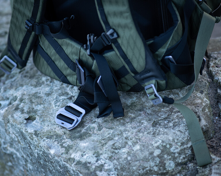 Black tactical backpack with straps and buckles resting on a textured concrete surface.