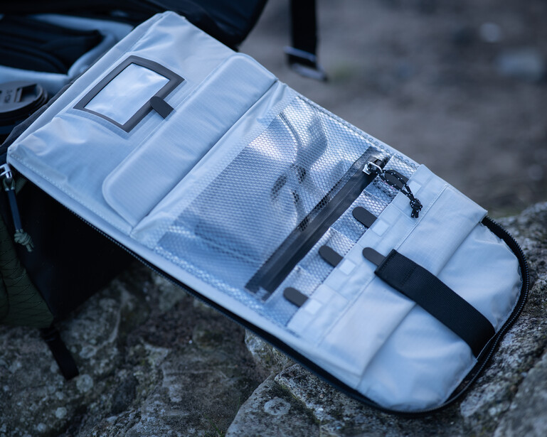 White organizer pouch with multiple compartments displaying cables, adapters, and small tech accessories.