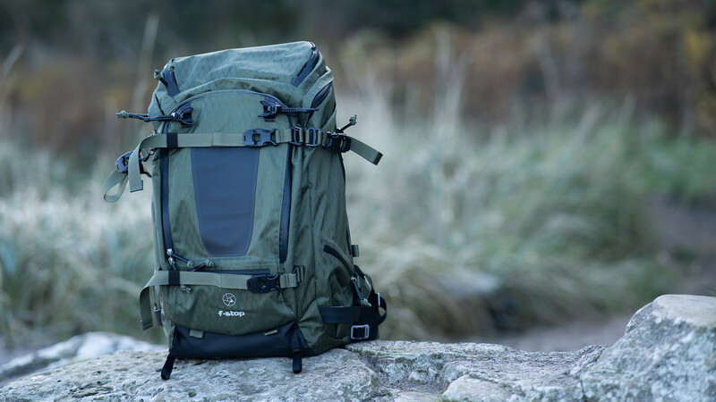 Gray and black hiking backpack positioned on a boulder in an arid landscape with shrubland in the background.