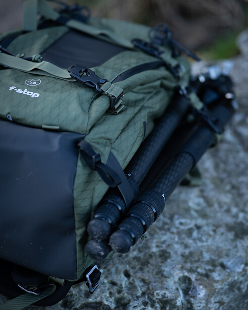 Tactical backpack and gear laid out on concrete surface with natural outdoor lighting.