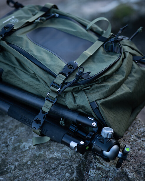 Tactical camera bag with mounted mirrorless camera on concrete surface.