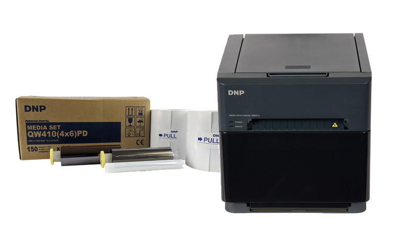 DNP photo printer with media set box and paper rolls displayed alongside the device.