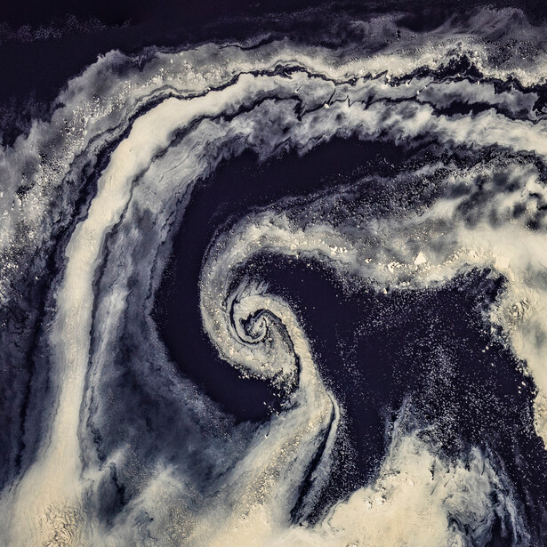 Satellite view of a spiral cloud formation over dark ocean waters.