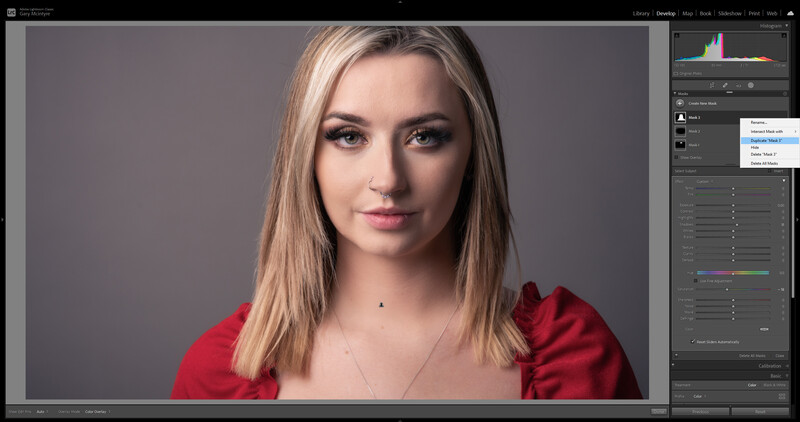 Woman with long blonde hair wearing a red shirt against a neutral gray background.