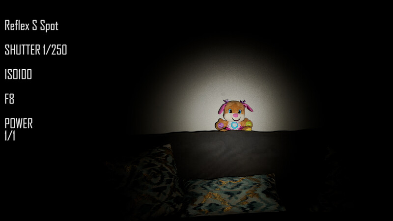 Colorful toy character peeking over a dark surface against a black background with dramatic spotlight lighting.