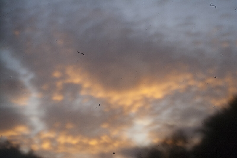 Dramatic sunset sky with golden-orange light breaking through layered gray clouds.