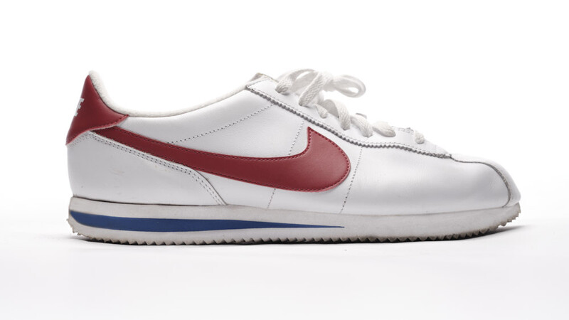 White leather sneaker with burgundy and navy swoosh and heel tab on neutral background.